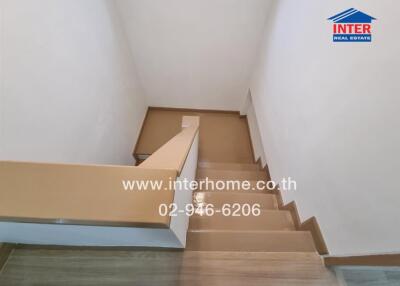 Staircase with wooden steps and beige handrail