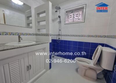 Bathroom with blue and white tile design, sink, mirror, shower, and toilet