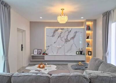Modern living room with gray sofa, marble accent wall, and built-in shelves