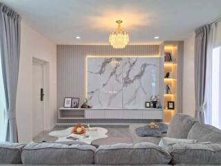 Modern living room with gray sofa, marble accent wall, and built-in shelves