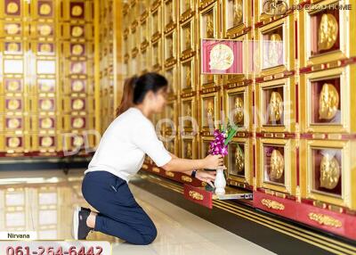 Person placing flowers in front of golden niches