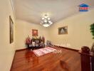 Spacious living room with wooden flooring, chandelier, artwork, and built-in shrine.