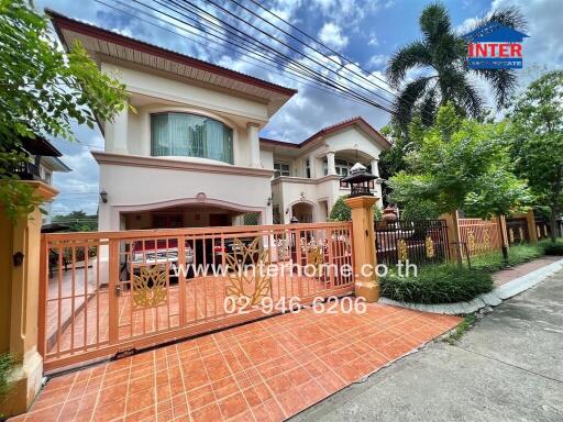 Front view of a two-story house with a gated entrance and spacious driveway