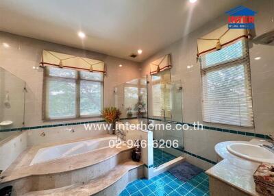Spacious bathroom with white and blue tiles, large bathtub, and glass-enclosed shower area