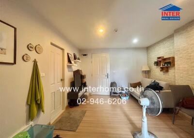 Comfortably furnished living room with light-colored wooden flooring and simple decor.