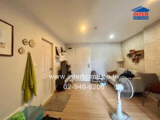 Comfortably furnished living room with light-colored wooden flooring and simple decor.