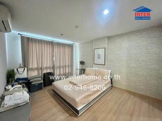 Spacious bedroom with minimalist decor, featuring a large window and modern furnishings.