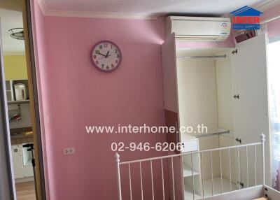 Bedroom with open wardrobe, wall clock, and air conditioning unit