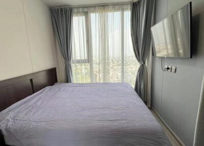 Bedroom with a large bed, mounted TV, and large windows with grey curtains