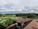 View of a rooftop with surrounding greenery and distant clouds