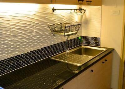 Modern kitchen with black countertop, double sink, and wooden cabinets.