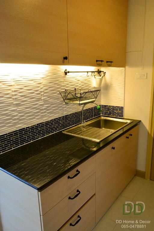 Modern kitchen with black countertop, double sink, and wooden cabinets.