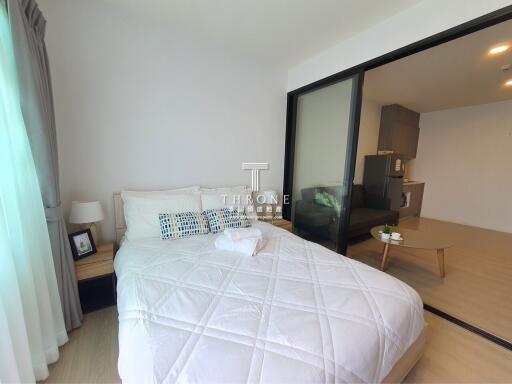 Well-furnished bedroom with view into a small adjacent living area and kitchen.