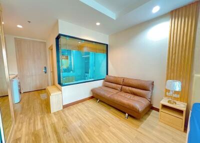 Modern living room with a glass partition, brown leather sofa, and wooden flooring