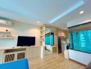 Modern living room with wooden flooring, built-in shelves, TV, and large glass window.