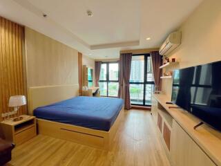 Modern bedroom with large bed, window view, and wooden flooring