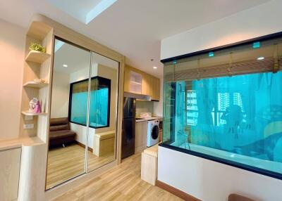modern apartment living area with sliding mirror doors, couch, large window, washing machine, refrigerator, and aquarium