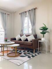 Well-decorated living room with sofa, coffee tables, and plants