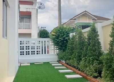 Well-maintained backyard with artificial grass and stepping stones