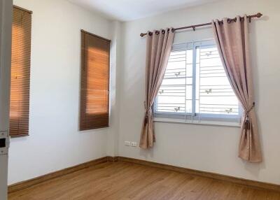 empty bedroom with wooden floor, window with brown curtains and blinds