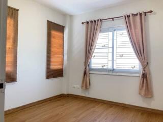 empty bedroom with wooden floor, window with brown curtains and blinds