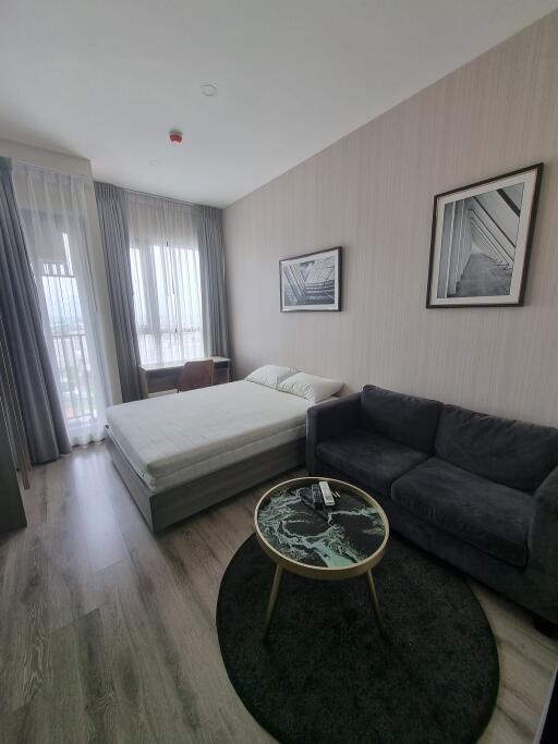 Bedroom with a bed, sofa, round coffee table, and wall art