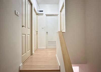 A hallway with beige doors and wooden flooring