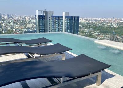 Modern rooftop swimming pool area with lounge chairs and city views