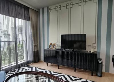 Modern living room with a TV, patterned rug, coffee table, and large window