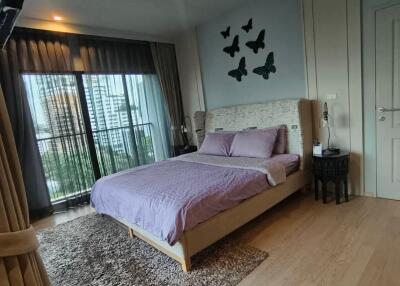 Cozy bedroom with a large bed, decorative butterflies on the wall, and balcony access.