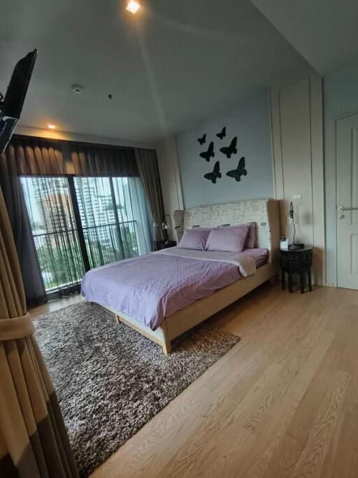 Cozy bedroom with a large bed, decorative butterflies on the wall, and balcony access.