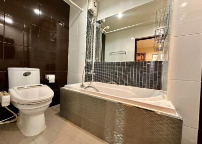 Modern bathroom with toilet, bathtub, and large mirror