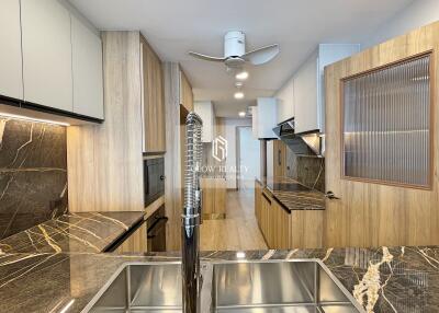 Modern kitchen with marble countertops, wooden cabinets, and stainless steel fixtures