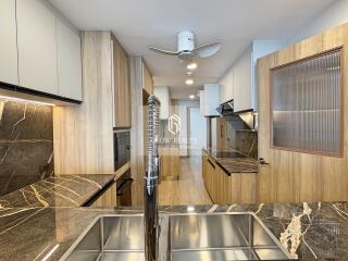 Modern kitchen with marble countertops, wooden cabinets, and stainless steel fixtures