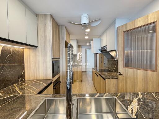 Modern kitchen with marble countertops, wooden cabinets, and stainless steel fixtures