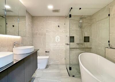 Modern bathroom with large glass shower, freestanding bathtub, vanity with two sinks, and toilet