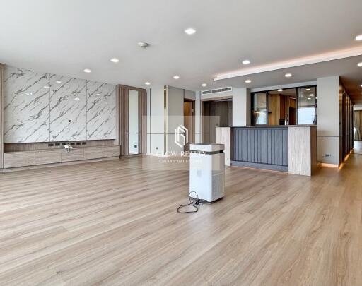 Spacious modern living area with wooden flooring, built-in cabinets, and a kitchen island