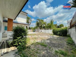 Spacious backyard view with greenery and side of house.