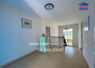 Bright hallway with wooden flooring and a staircase railing