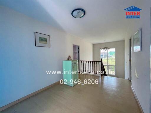 Bright hallway with wooden flooring and a staircase railing