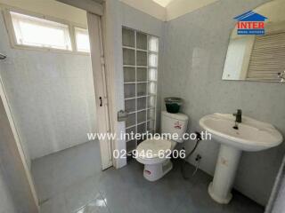 Bathroom with sink, toilet, and glass block wall