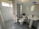 Bathroom with sink, toilet, and glass block wall