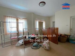 Cluttered bedroom with hanging clothes rack and various items on the floor