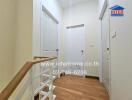 A hallway with three white doors and wooden flooring.