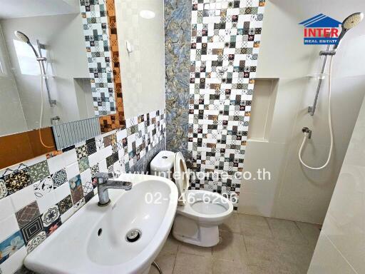 Bathroom with a sink, toilet, and shower area with decorative tiling