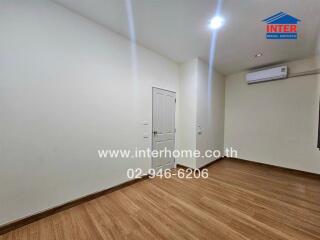 Spacious bedroom with wooden floor and air conditioning