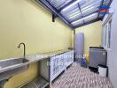 Utility room with stainless steel sink, storage cabinets, washing machine, and water heater