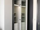 Modern wardrobe with open doors in a bedroom showing shelves and drawers