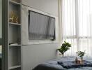 Bedroom with wall-mounted TV, air conditioner, and large window