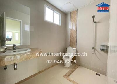 Modern bathroom with beige tones, sink, toilet, and shower area